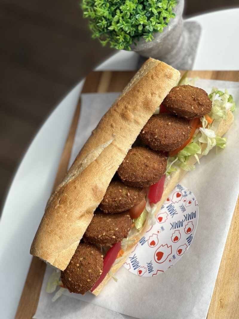 Falafel-Sandwich mit frischem Gemüse in einem knusprigen Brötchen, serviert bei MMK.