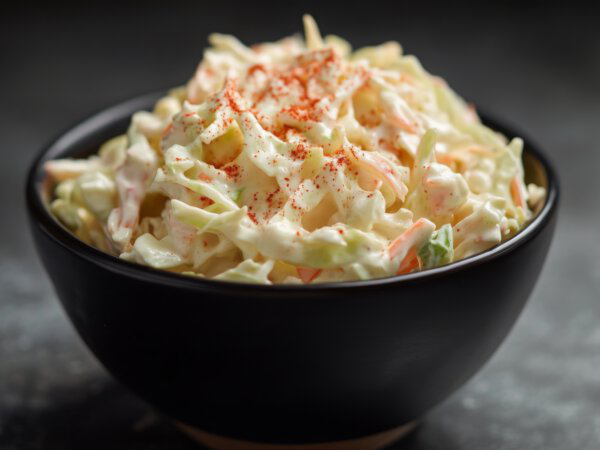 Cremiger Krautsalat mit Paprikapulver in schwarzem Schüssel, ideal als Beilage im Online Shop.