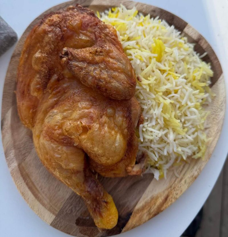 gegrilltes halbes huhn mit reis auf holzteller halal fried chicken zell am see streetfood